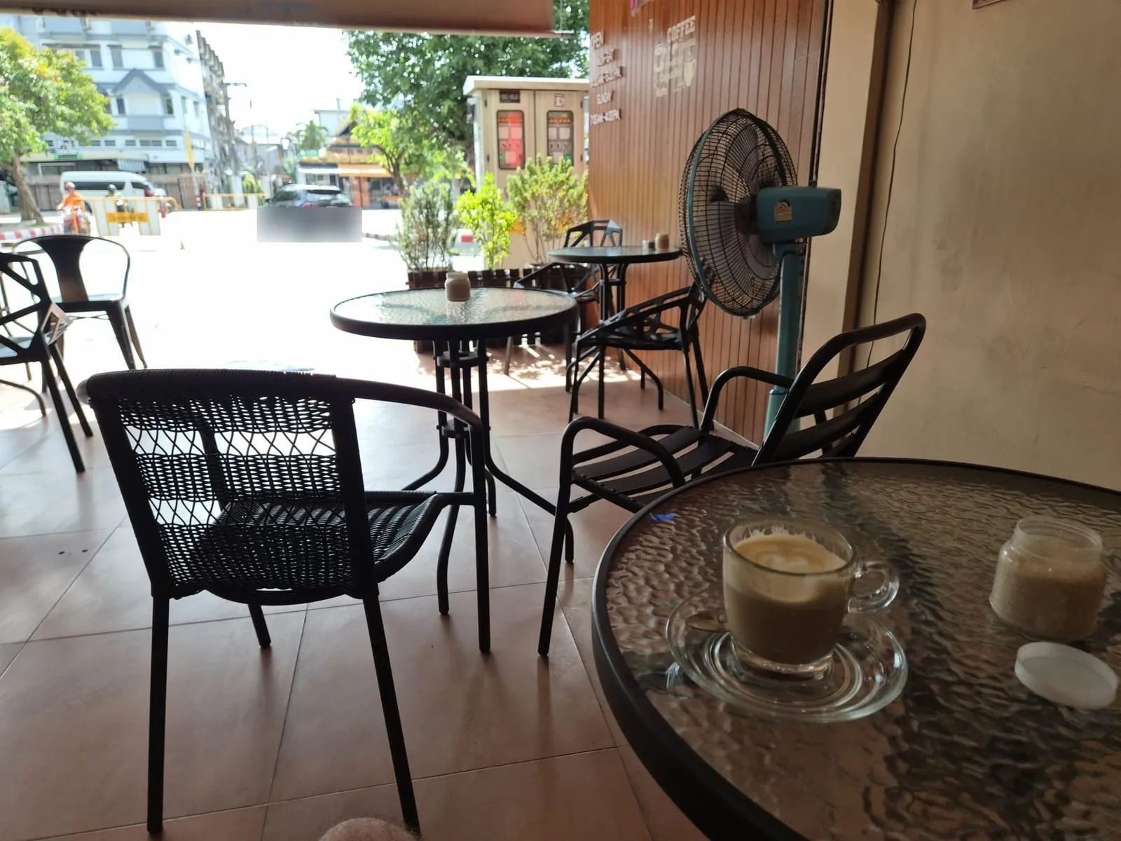 Un caffè su un tavolino di vetro, in un locale aperto sulla strada a Chiang Mai
