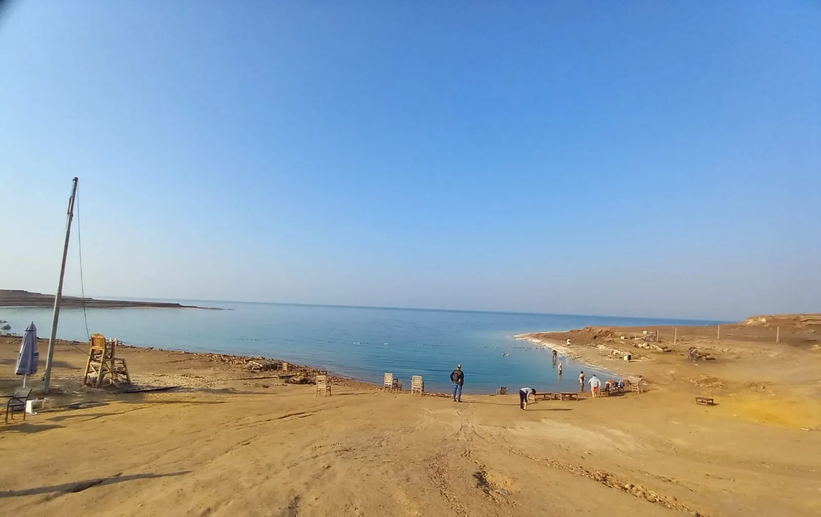 Una spiaggia sul Mar Morto, con l’acqua azzurra e qualche persona in riva