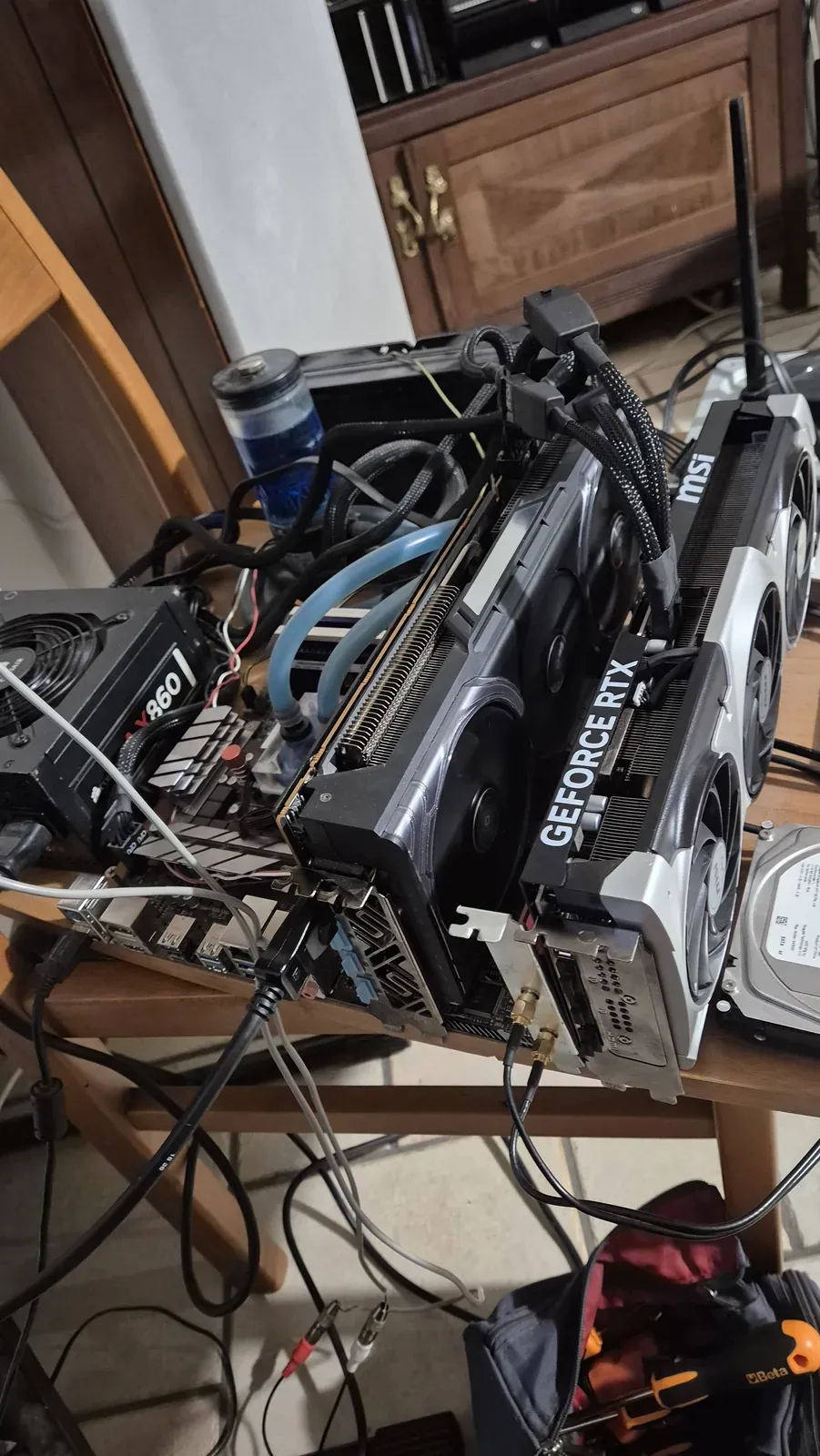 Un PC montato sul banco con schede video, tubi azzurri e numerosi cavi collegati