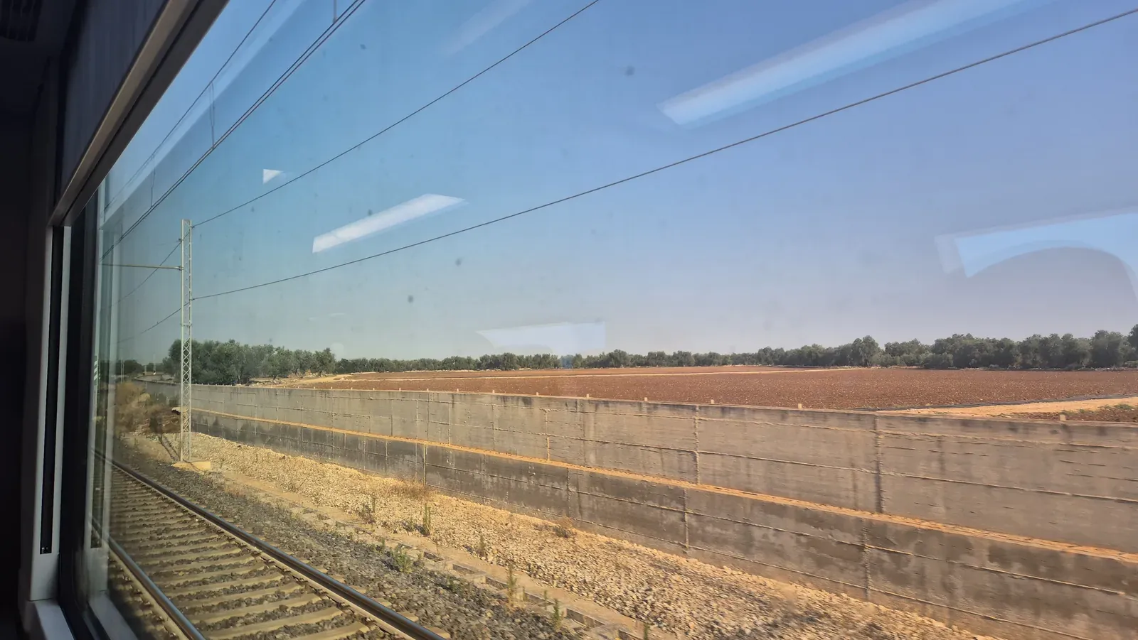 Campi e binari fotografati dal finestrino del treno durante il viaggio in Puglia