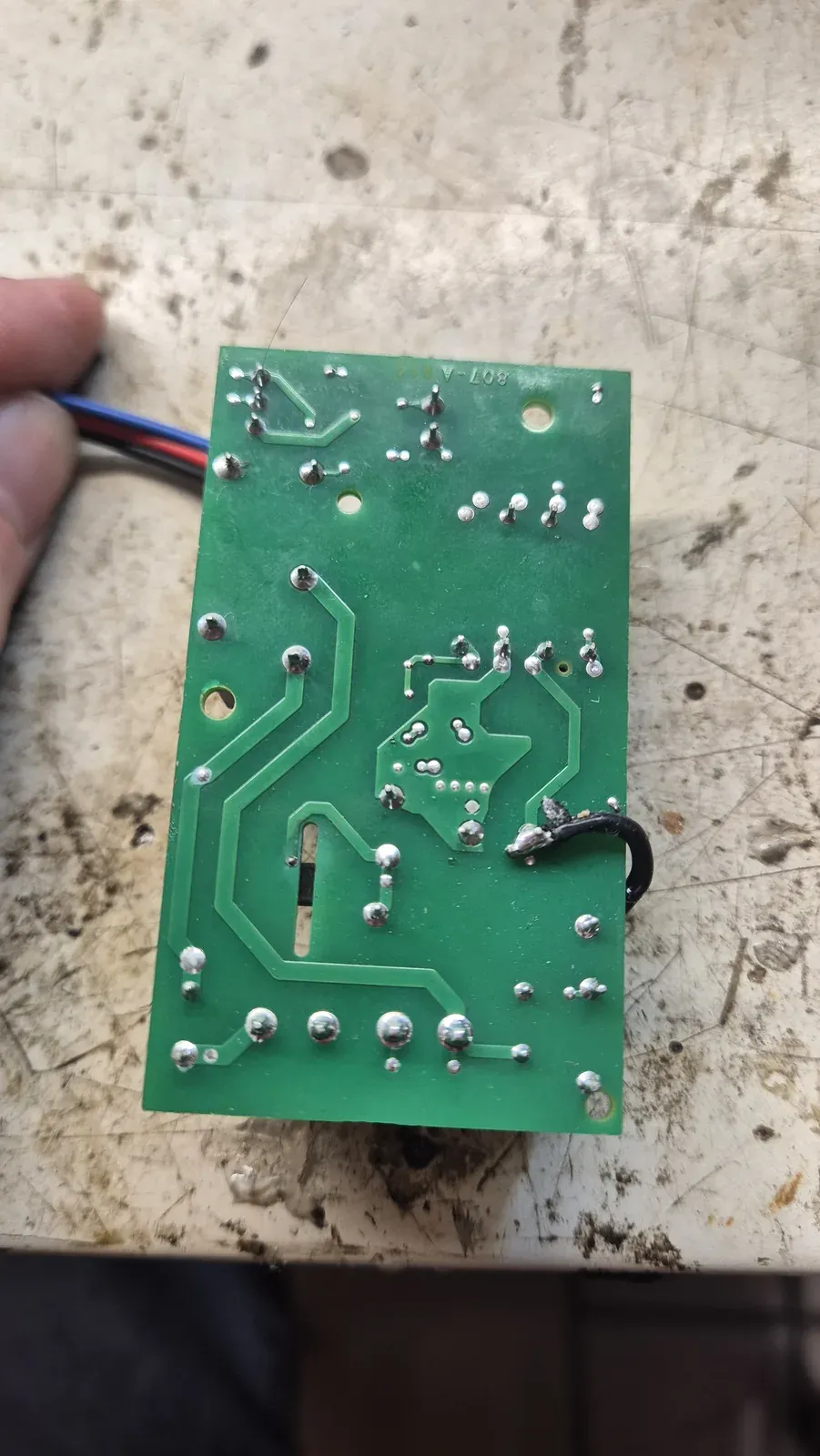 Il retro della scheda elettronica tenuta in mano, con le piste e i punti di saldatura visibili