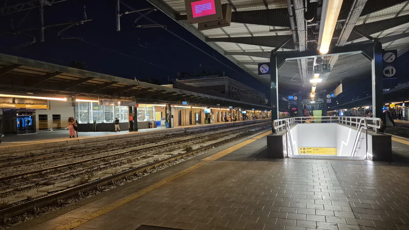 I binari e le banchine illuminate della stazione di Bari Centrale di sera