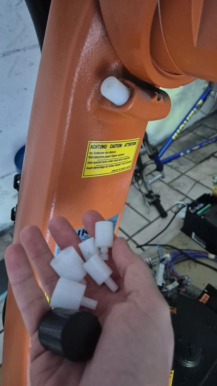Finecorsa meccanici bianchi in plastica tenuti in mano accanto al braccio del robot, uno già montato